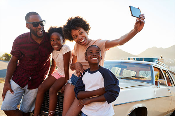 family of 4 taking a selfie in front of a landscape