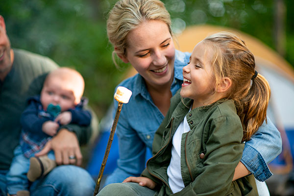 mom and daughter roasting marshmallow by campfire