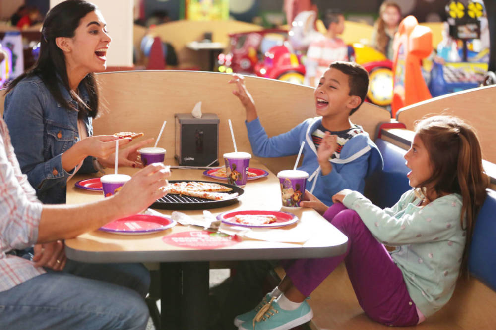 Family laughing at table over some pizza