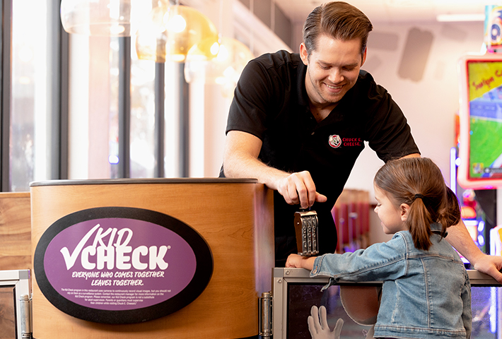عضو فريق تشكي تشيز يختم ذراع فتاة صغيرة لنظام Kid Check.