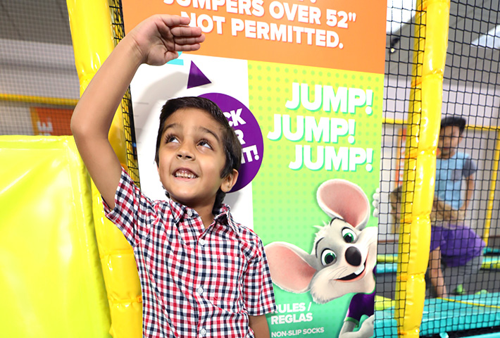 Kid holding his hand up to the height requirement for the trampoline zone